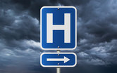 Hospital directional sign with storm clouds gathering behind it